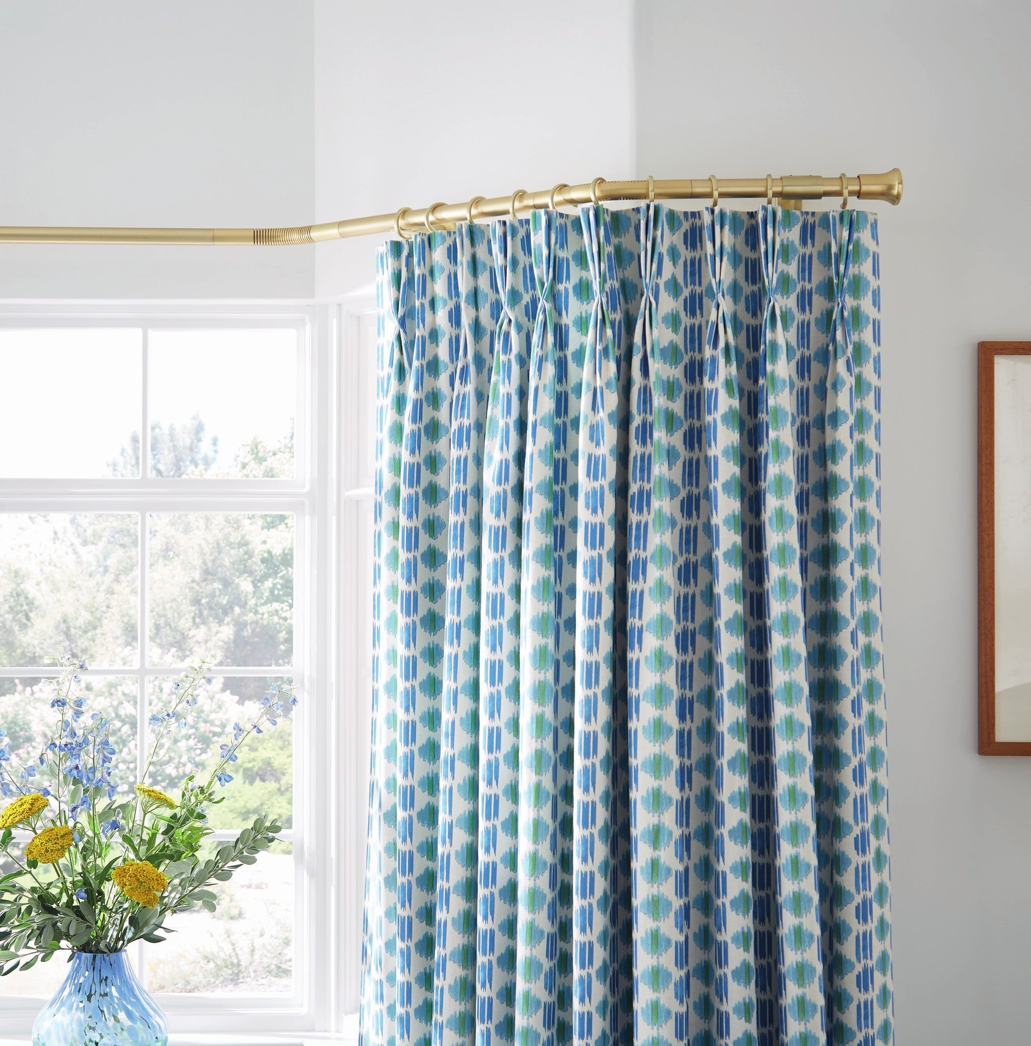 Hallis Neo gold bay window pole with Trumpet finials, fitted in a three-sided bay